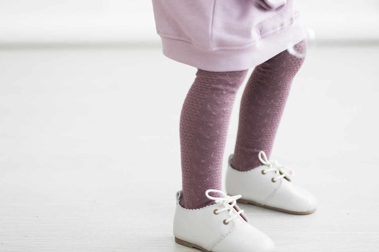 Girl wearing Shoes by Wander and Knitted Footed Tights in Deep Violet, all designed by Burrow and Be