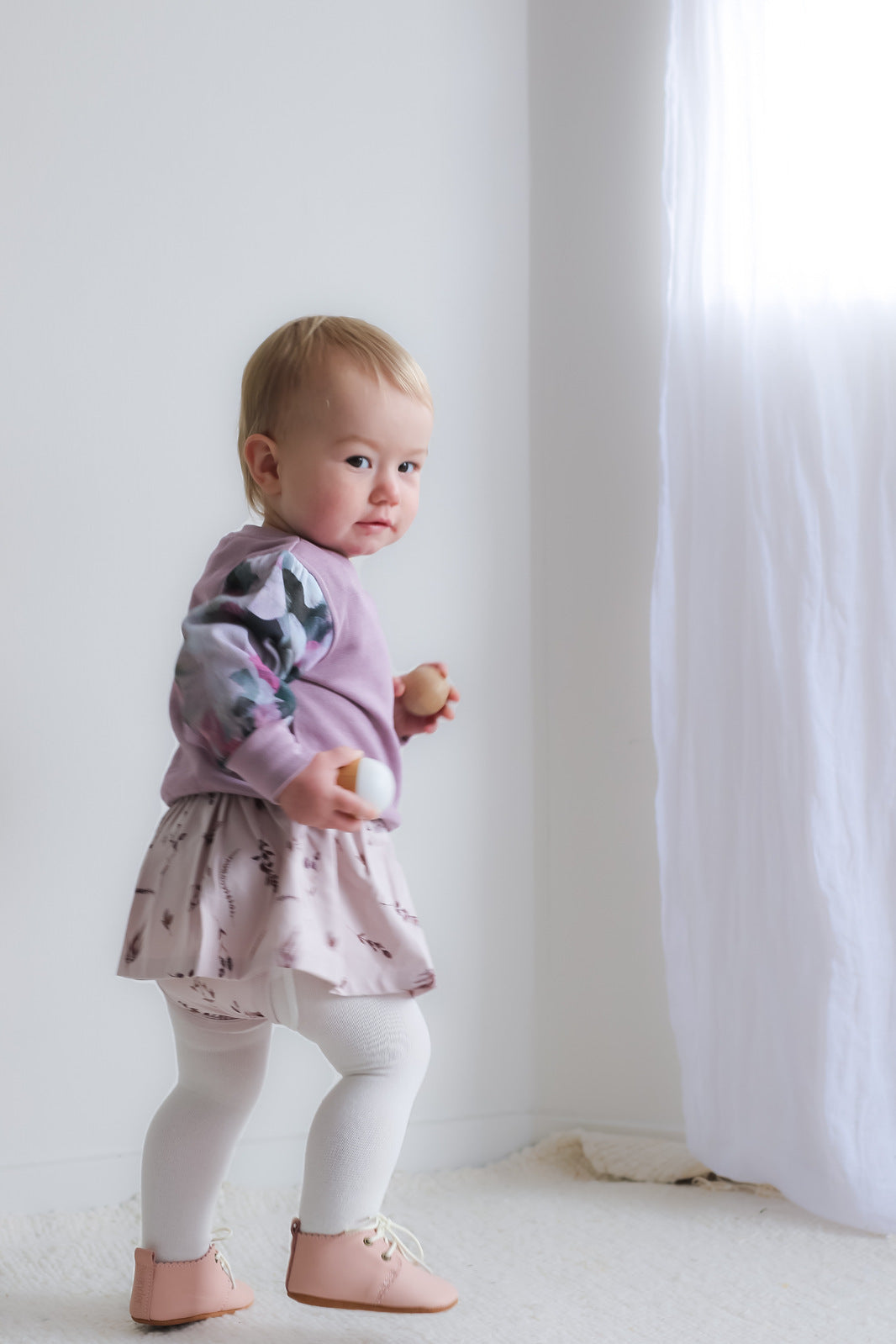 Girl in Violet Long Sleeve Sweater, Baby Dress, Shoes by Wanders and Knitted Footed Tights in White, all designed by Burrow and Be