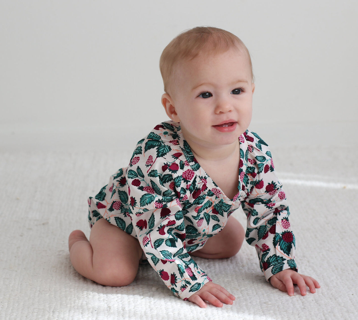 Baby wearing a floral patterned onesie on a white background