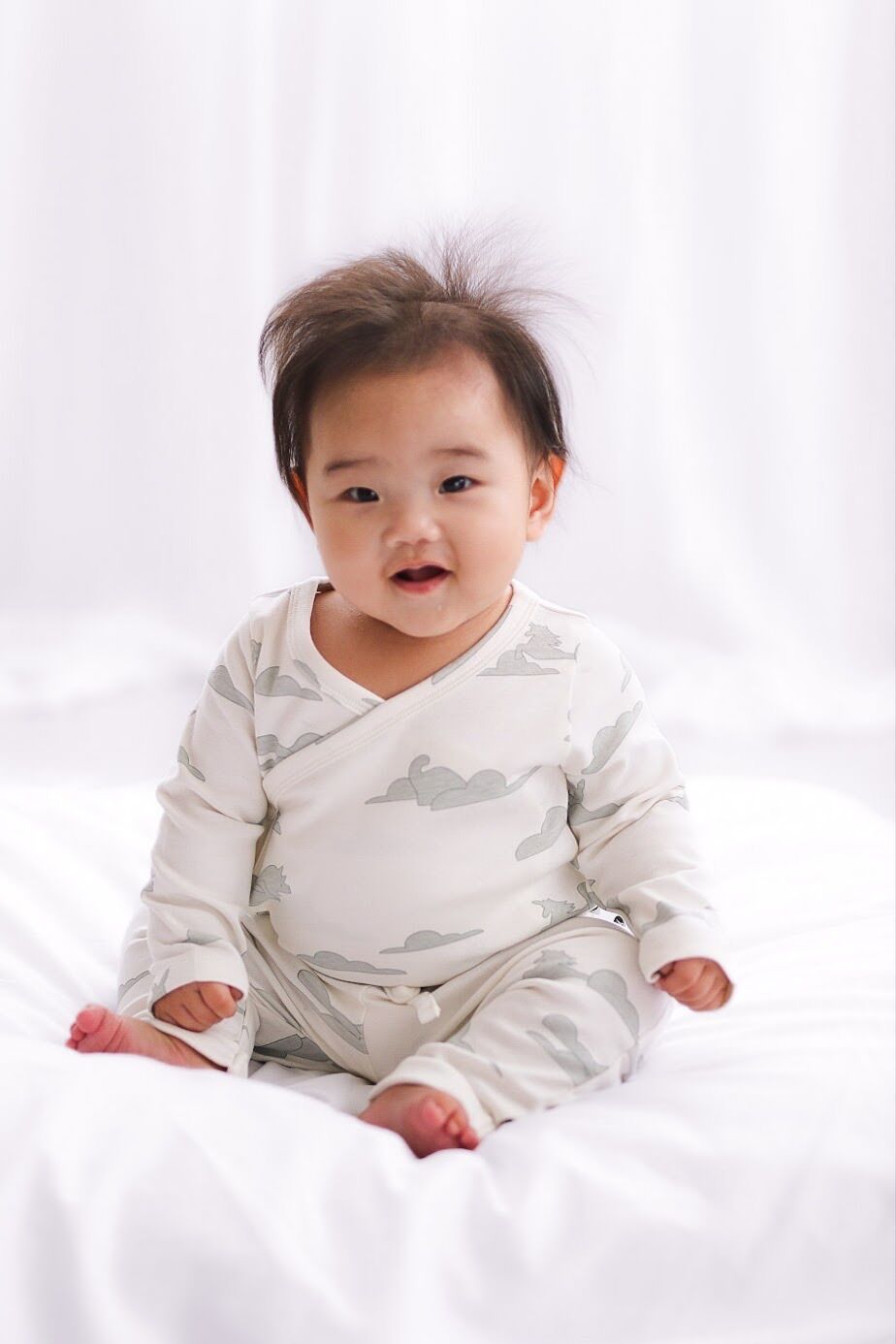 Baby wearing a white wrap with cloud pattern on a white background