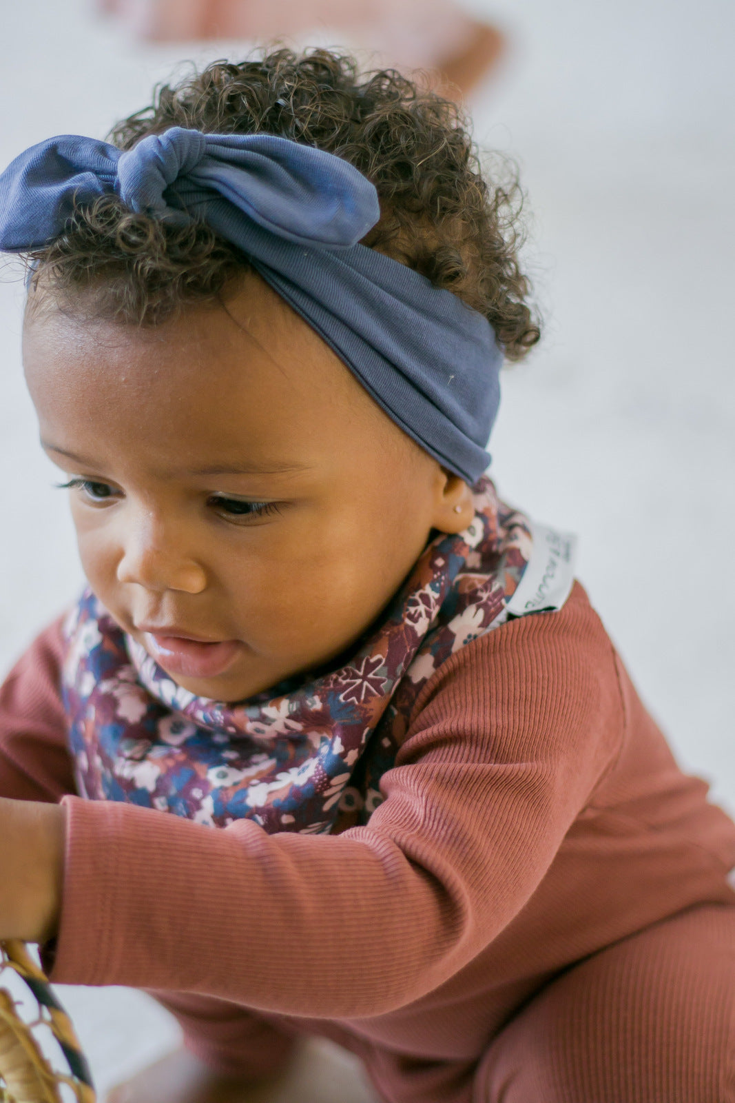 Baby girl wearing Rib bodysuit, dribble bib and Essential Baby Headband in Ink Blue, all designed by Burrow and Be