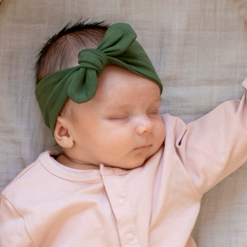 Baby girl wearing Sleepsuit in Natural colour and Essential Baby Headband in Pine, designed by Burrow and Be
