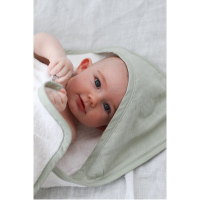 Baby wrapped in Sage Essential Baby Hooded Towel designed by Burrow and Be