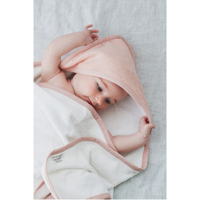 Baby wrapped in Blush Essential Baby Hooded Towel designed by Burrow and Be