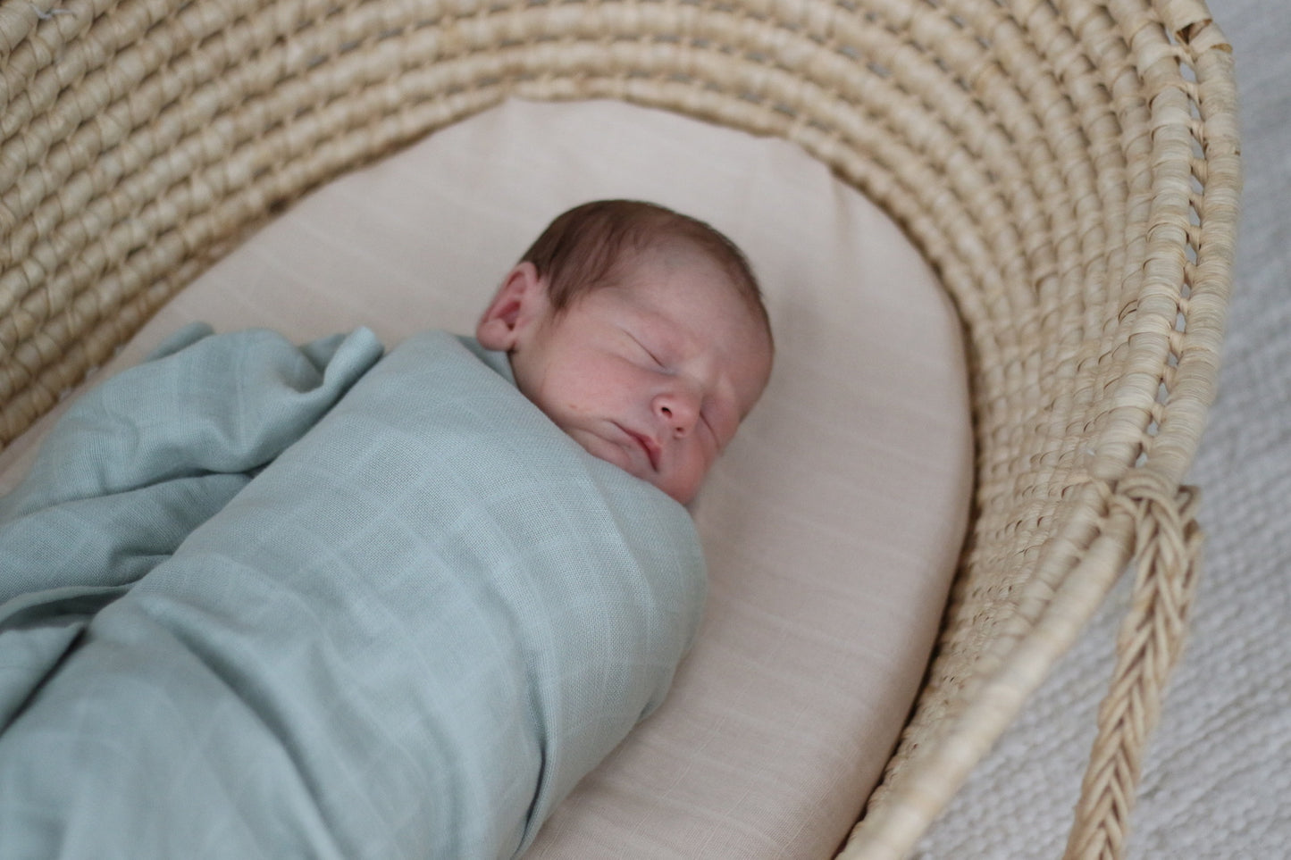 Baby in a Moses Basket wrapped in Essential Muslin Wrap in Grey, designed by Burrow and Be