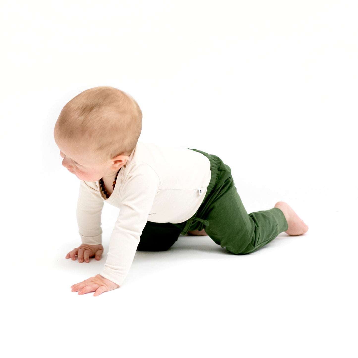 Baby crawling in white Bodysuit and Pine Essential Baby Jogger Pants by Burrow and Be