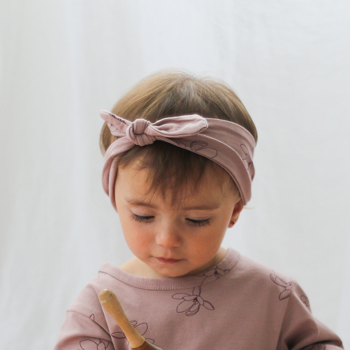 Baby girl wearing Hana Top and Essential Baby Headband both in Magnolia print, designed by Burrow and Be