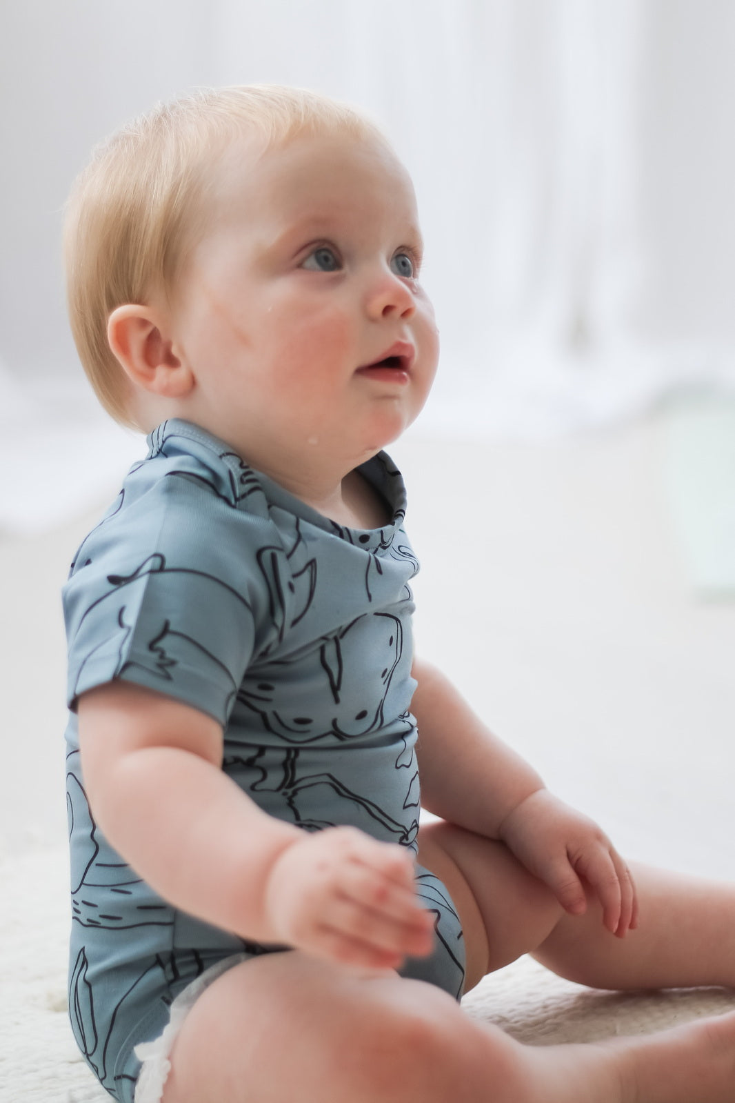 Baby posing and wearing Giant Bugs Short Sleeve Bodysuit, designed by Burrow and Be