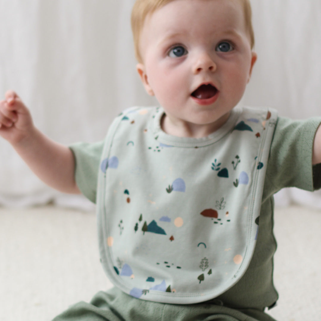 Baby wearing Burrow and Be Sage Pointelle short sleeve bodysuit and Garden Treasure Snuggle Bib