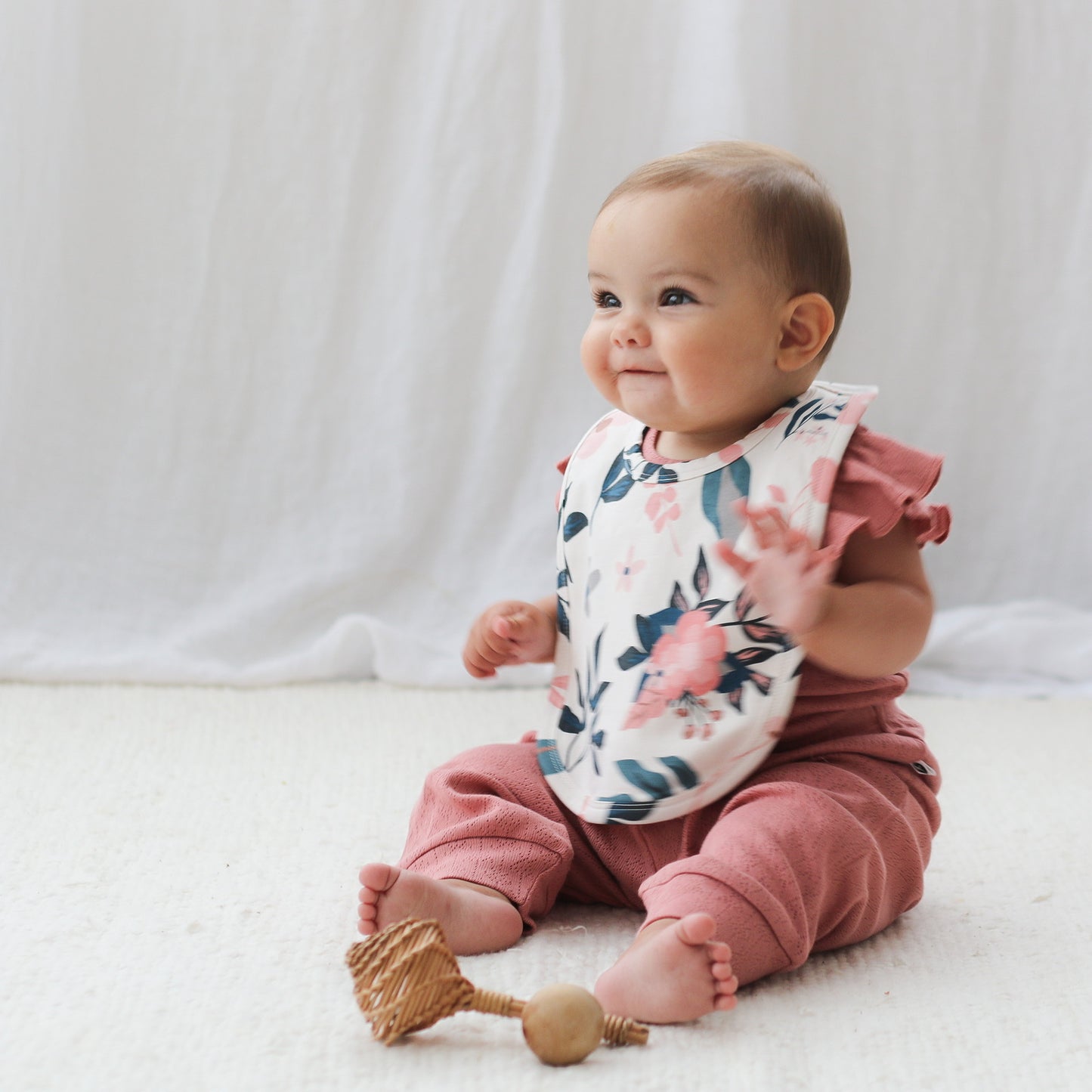 Baby girl wearing Burrow and Be Pink Clementine Snuggle Bib