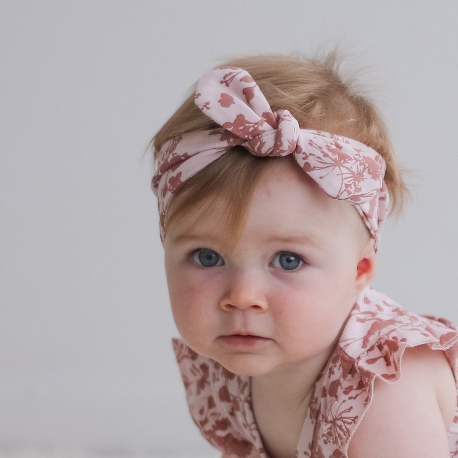 Baby girl wearing Flutter Baby Dress and Essential Baby Headband in Flower Splash  print, designed by Burrow and Be