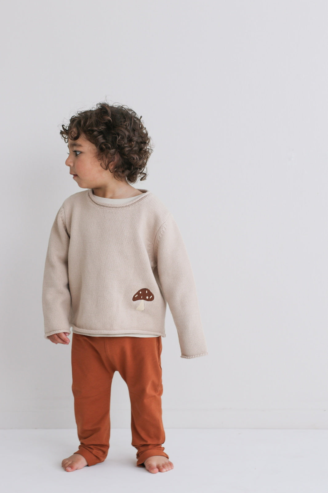 Boy standing in front of white background, wearing a sweater and Marley Pants - Chestnut, designed by Burrow and Be