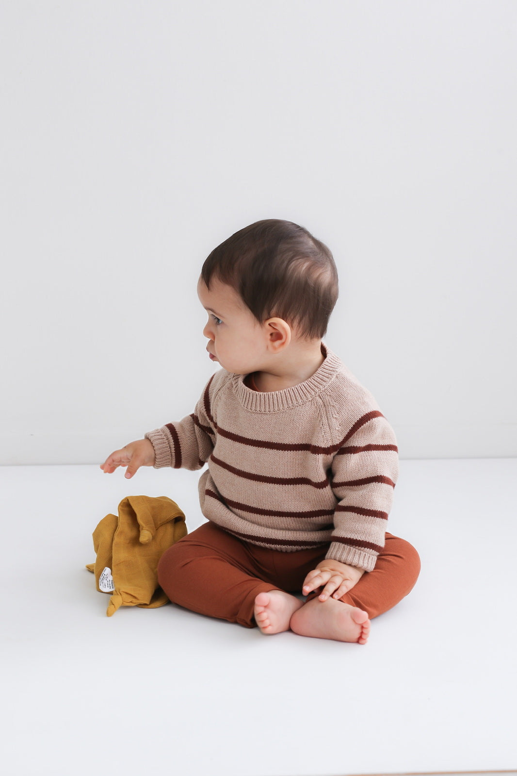 Baby sitting on floor in front of a white background and wearing Marley Pants - Chestnut, designed by Burrow and Be