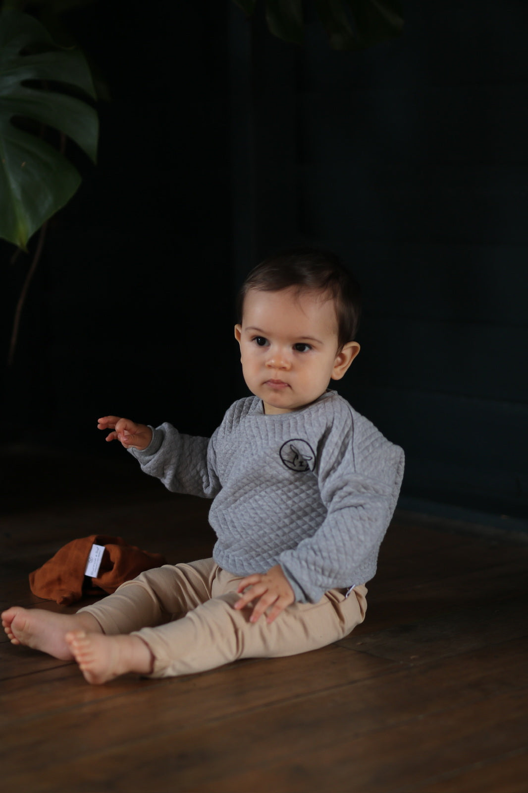 Baby sitting on wooden flooring, wearing Burrowers Long Sleeve Sweater and Marley Pants - Latte, designed by Burrow and Be