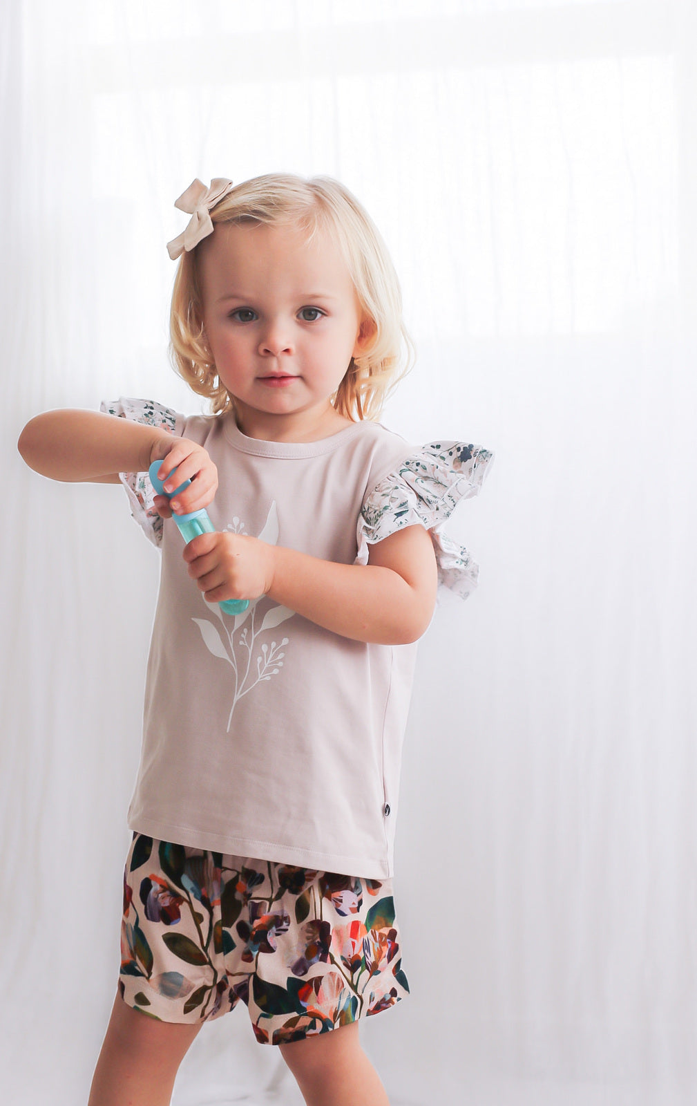 Girl posing at camera wearing Wildflower/Lavender Flutter T-shirt and Garden Party Lyla Shorts by Burrow and Be
