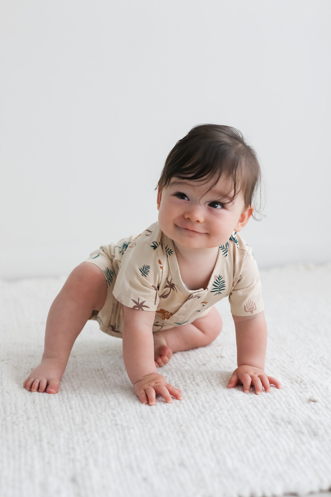 Baby smiling and crawling while wearing Jungle Stamp Alex Romper from Burrow and Be