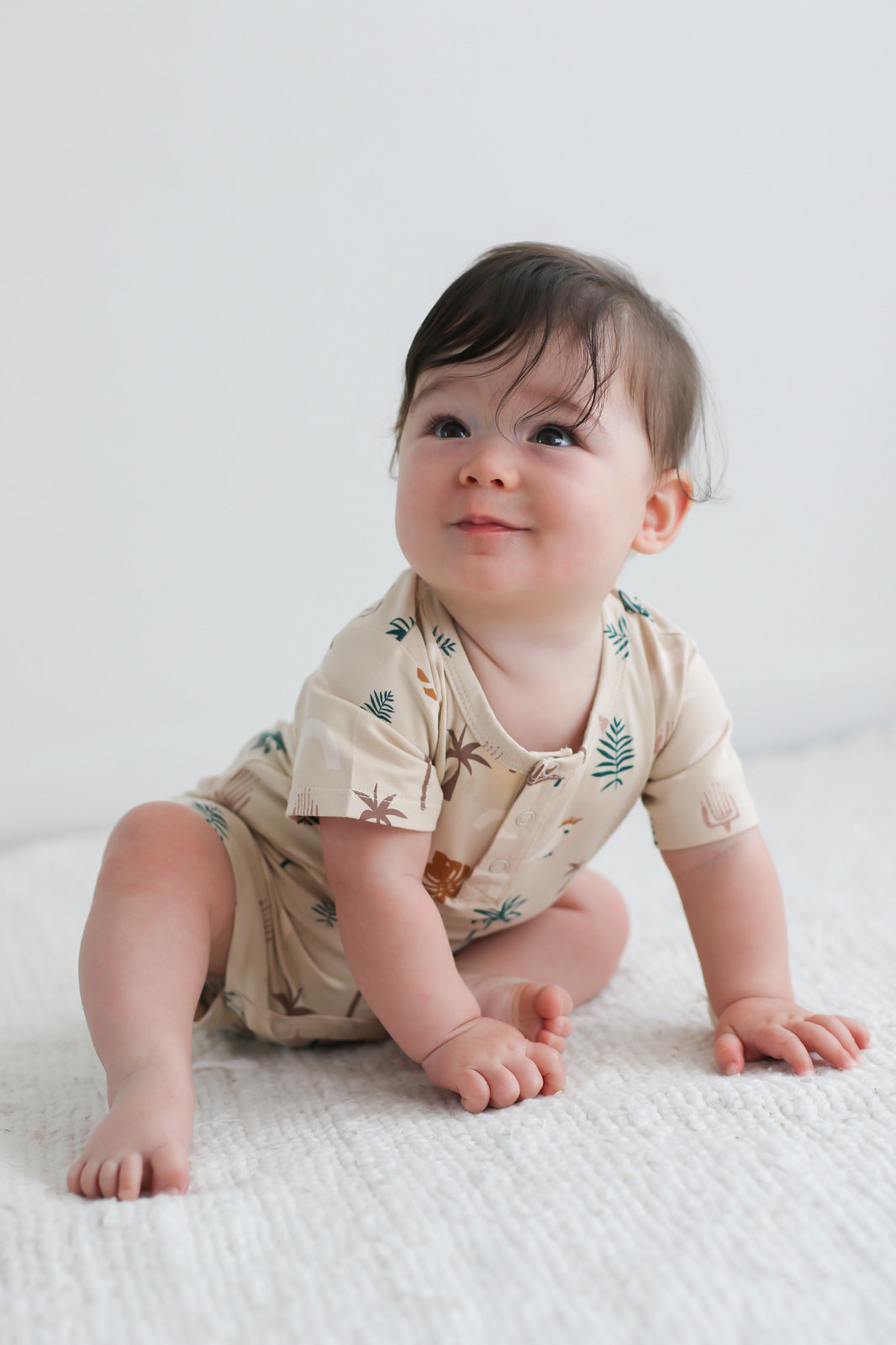 Baby smiling sweetly while wearing Jungle Stamp Alex Romper from Burrow and Be