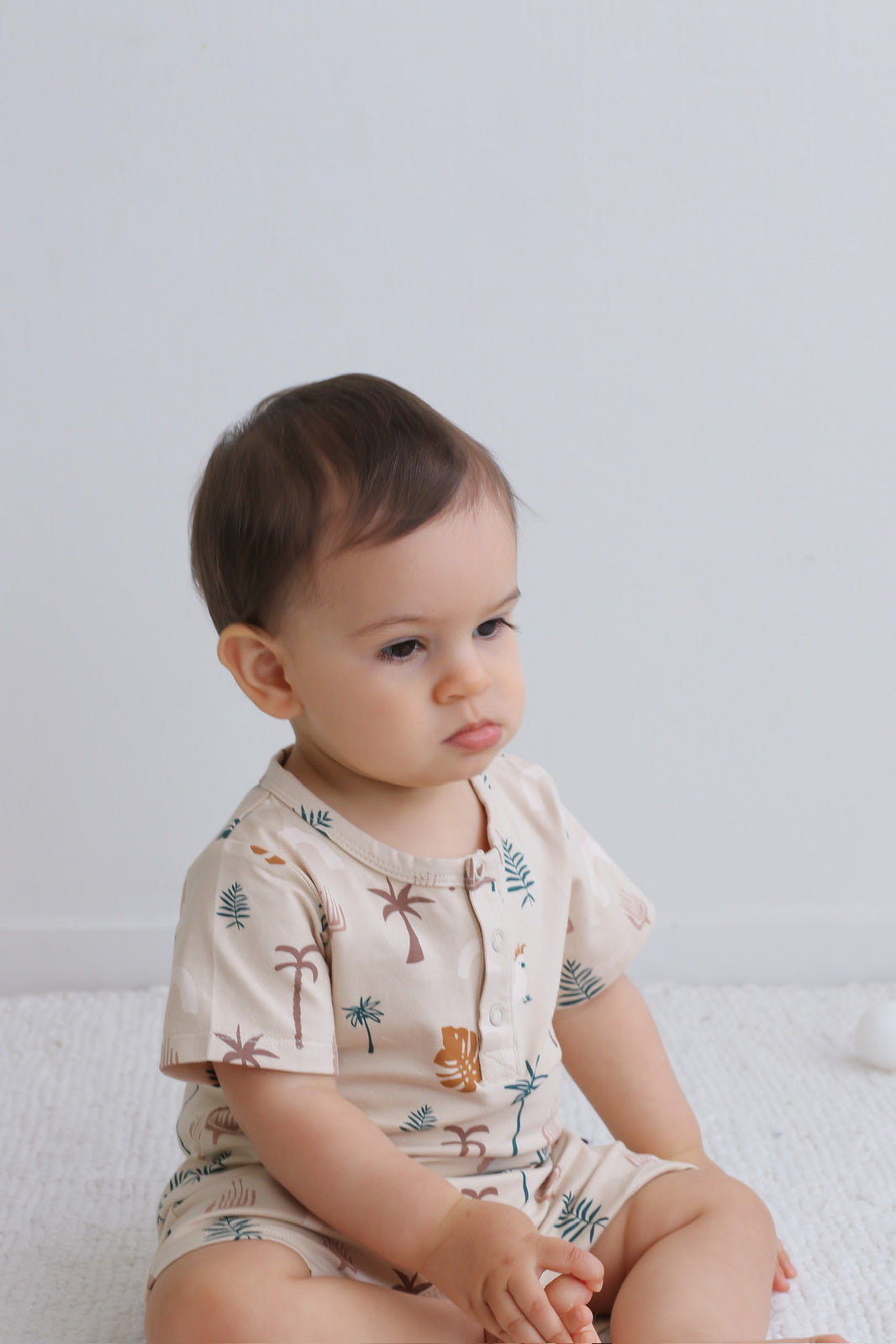 Baby wearing Jungle Stamp Alex Romper from Burrow and Be and looking cooly into distance