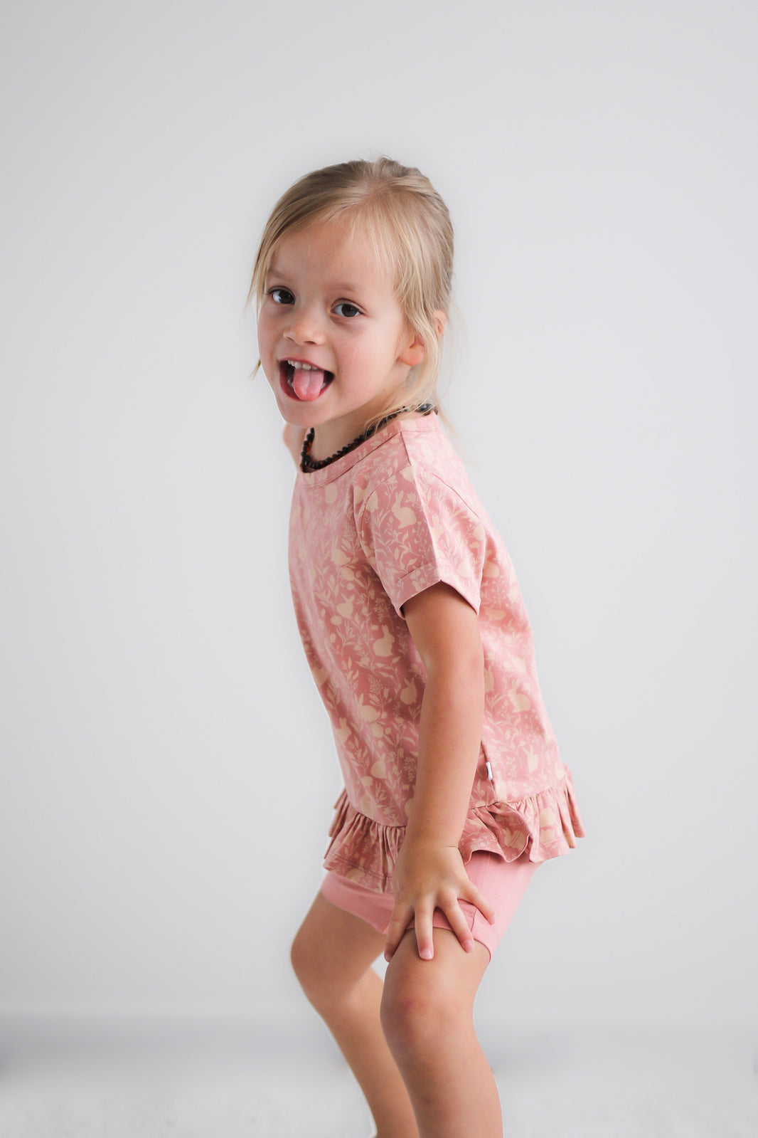 Girl posing in front of a white wall, wearing Mead-Doe Hana-Top and Mead Bike Shorts, both designed by Burrow and Be