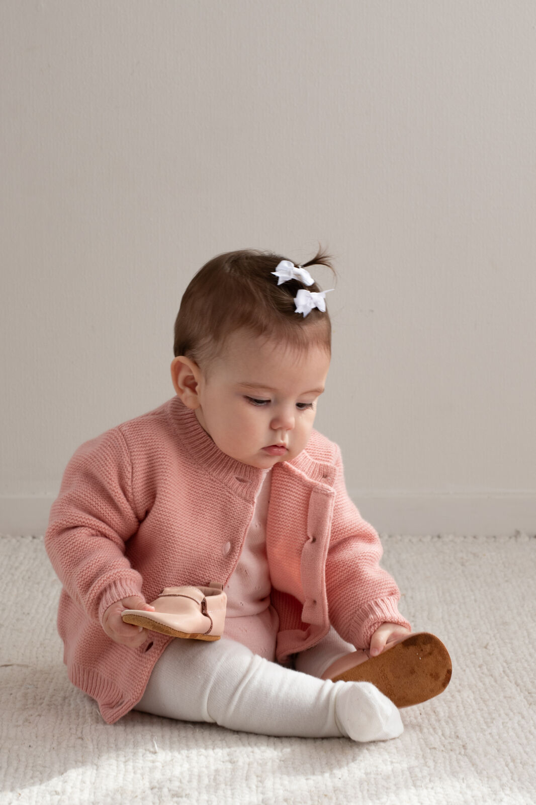 Child seated in 100% Wool Cardigan Carnation by Burrow and Be, pearl stitch and coconut buttons