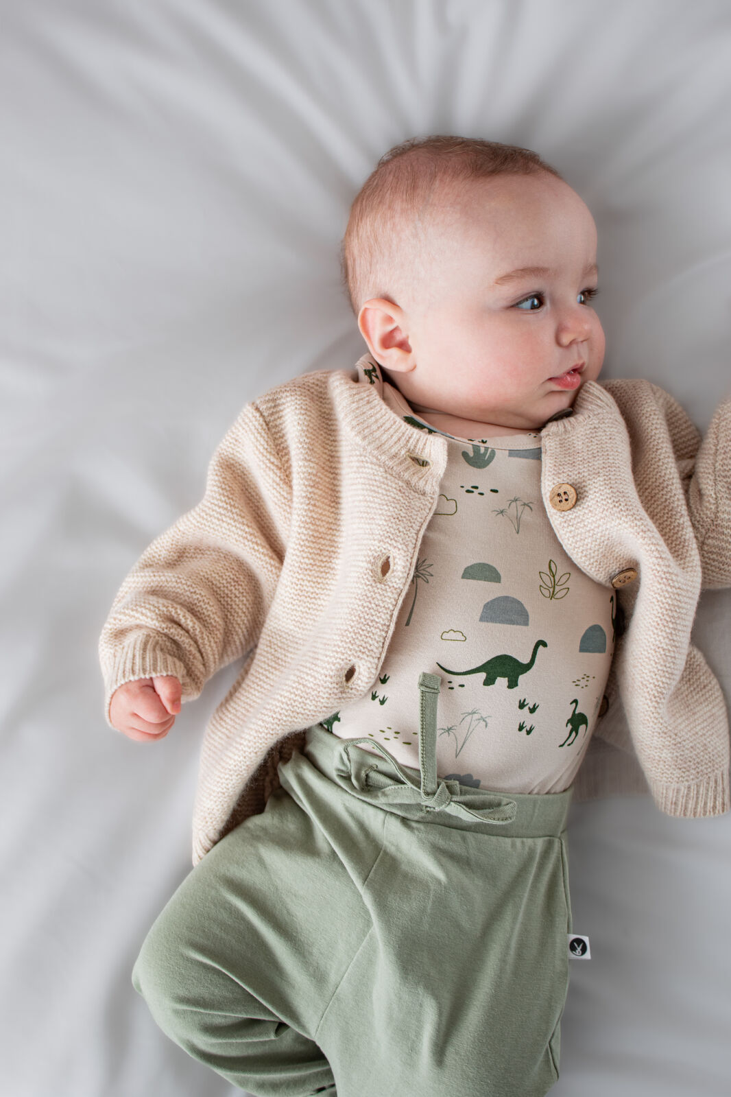 Baby lying in 100% Wool Cardigan Ecru by Burrow and Be, pearl stitch and coconut buttons