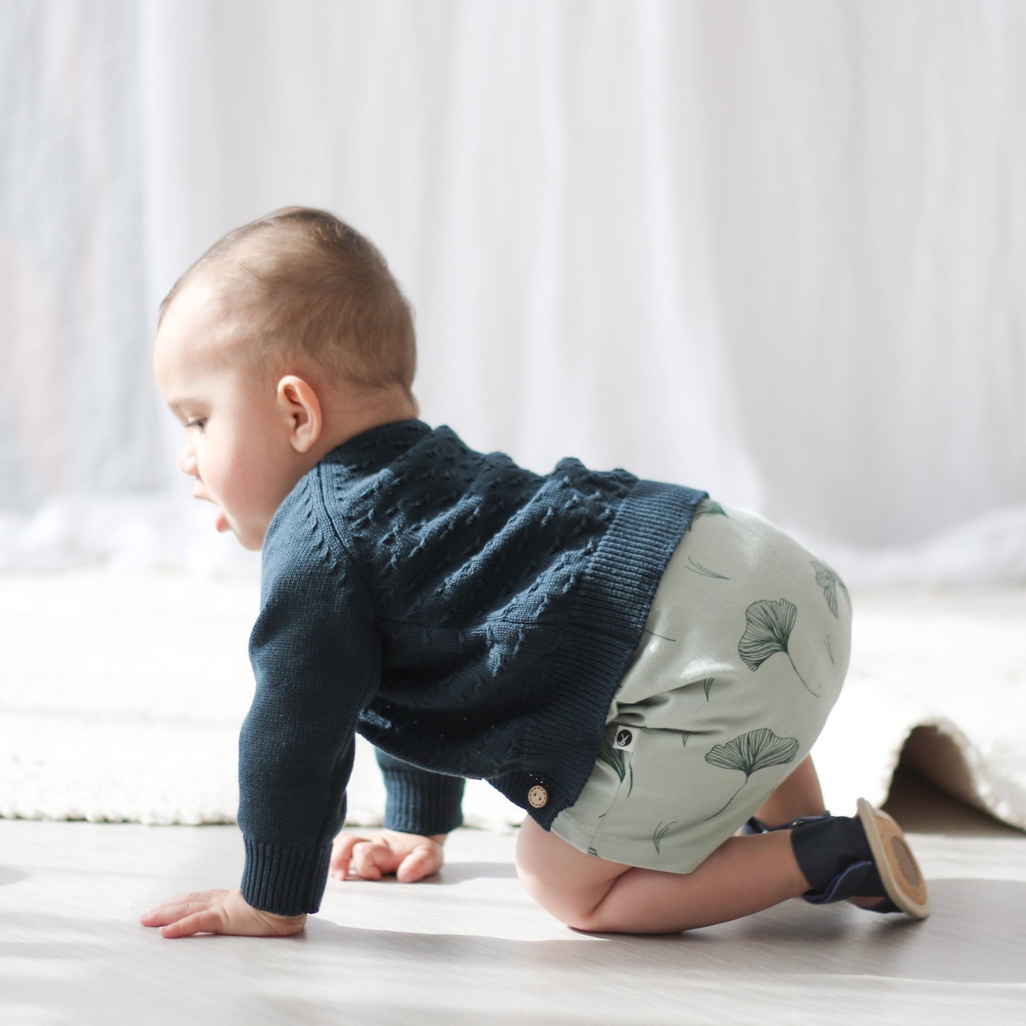 Baby wearing Ginkgo Alex Romper and Billie Knit Cardigan by Burrow and Be