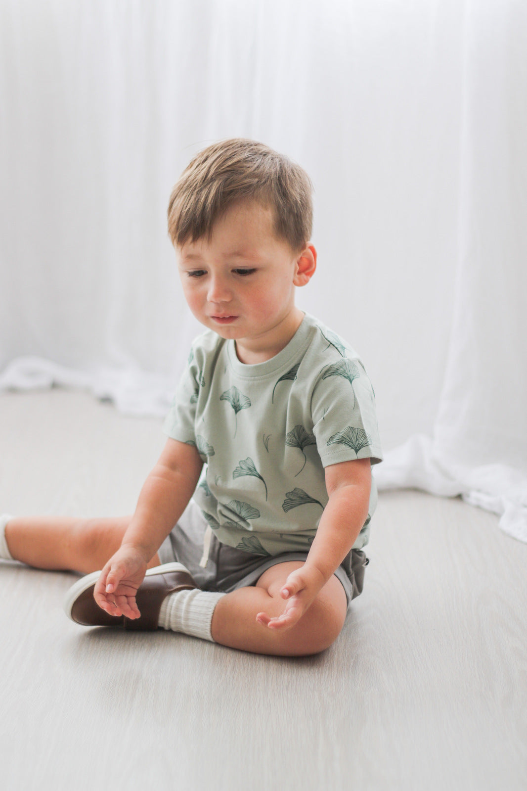 Toddler sitting on floor while wearing Sage Baby Short and Ginkgo Classic T-Shirt from Burrow and Be