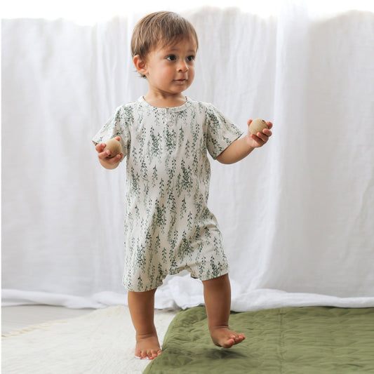 Toddler walking and holding two balls in an organic cotton Alex Romper on their first birthday, Burrow and Be Singapore