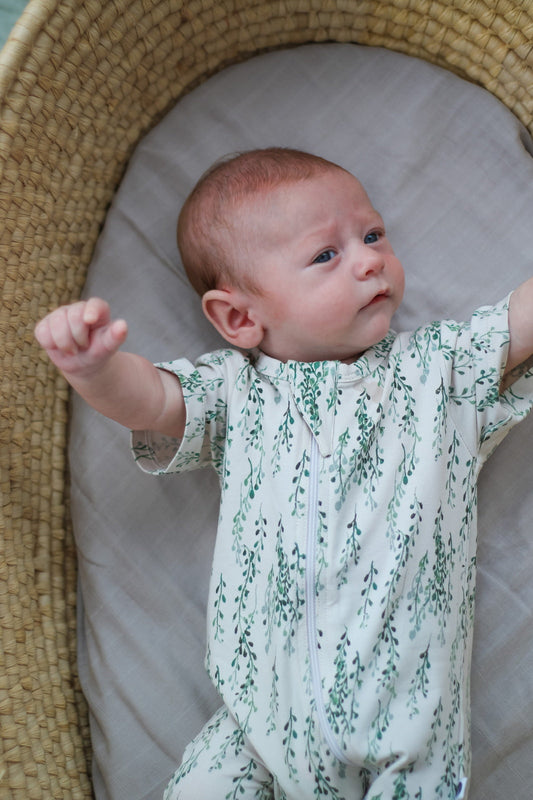 Baby settled in a Moses basket in an organic cotton zip suit on the night of the Mid-Autumn Festival, Burrow and Be Singapore
