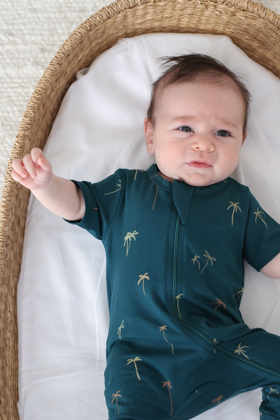 Baby asleep in a Moses basket in an organic cotton zip suit, Burrow and Be Singapore