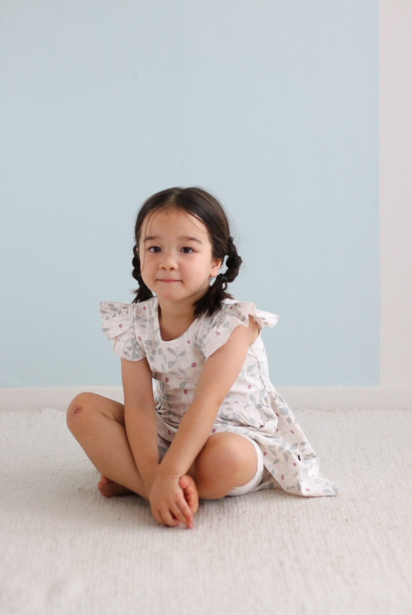 Young girl sitting on a light-colored surface with a light blue background