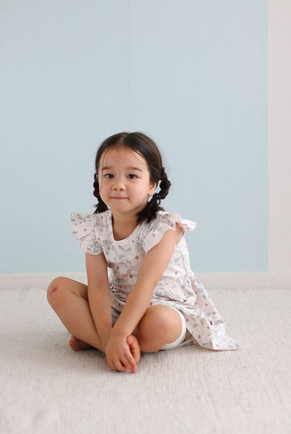 Young girl sitting on a light-colored surface with a light blue background