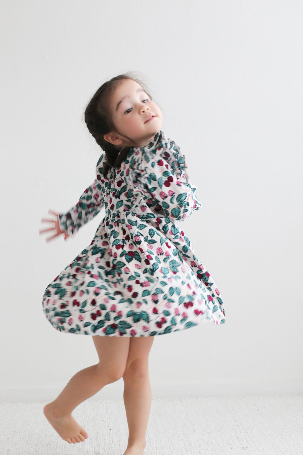 Child wearing a floral dress on a plain background