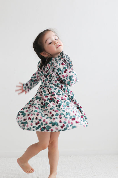 Child wearing a floral dress on a plain background