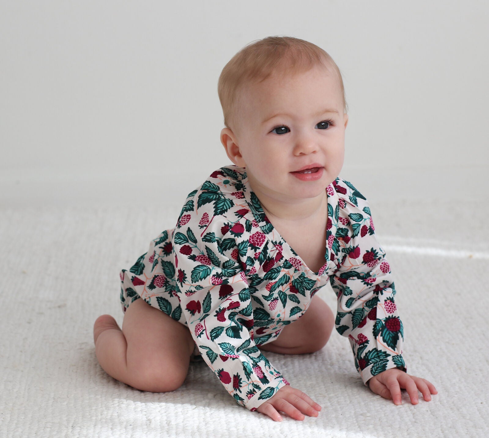 Baby wearing a floral patterned onesie on a white background