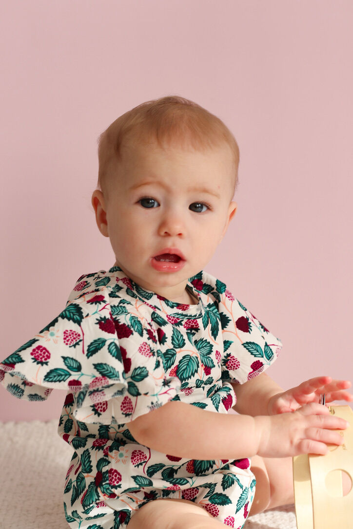 Baby wearing a floral outfit against a pink background