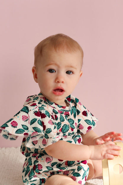 Baby wearing a floral outfit against a pink background