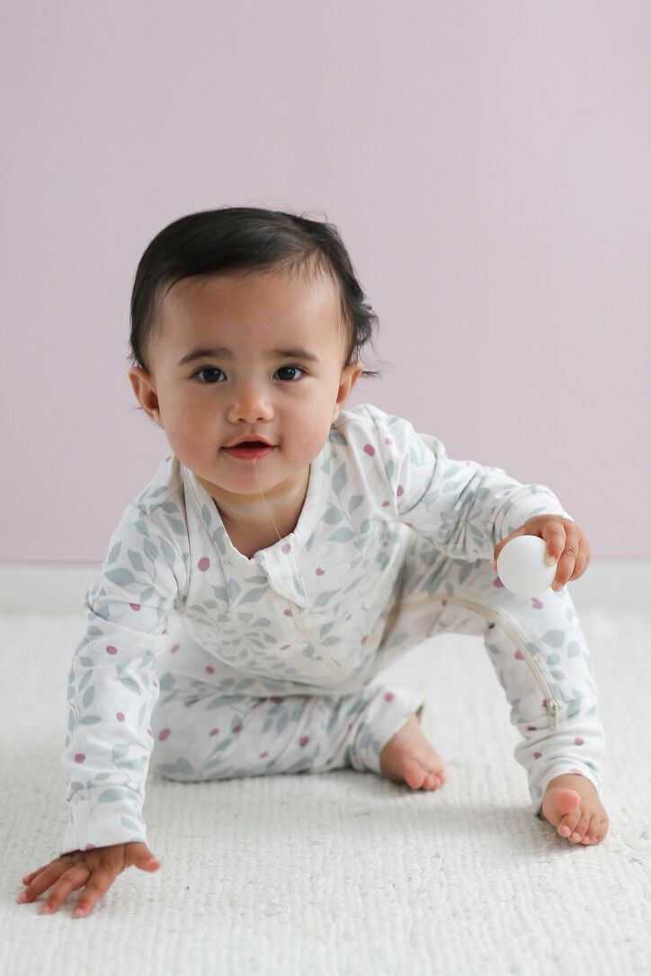 Baby wearing a white long-sleeve shirt with small patterns on a light pink background