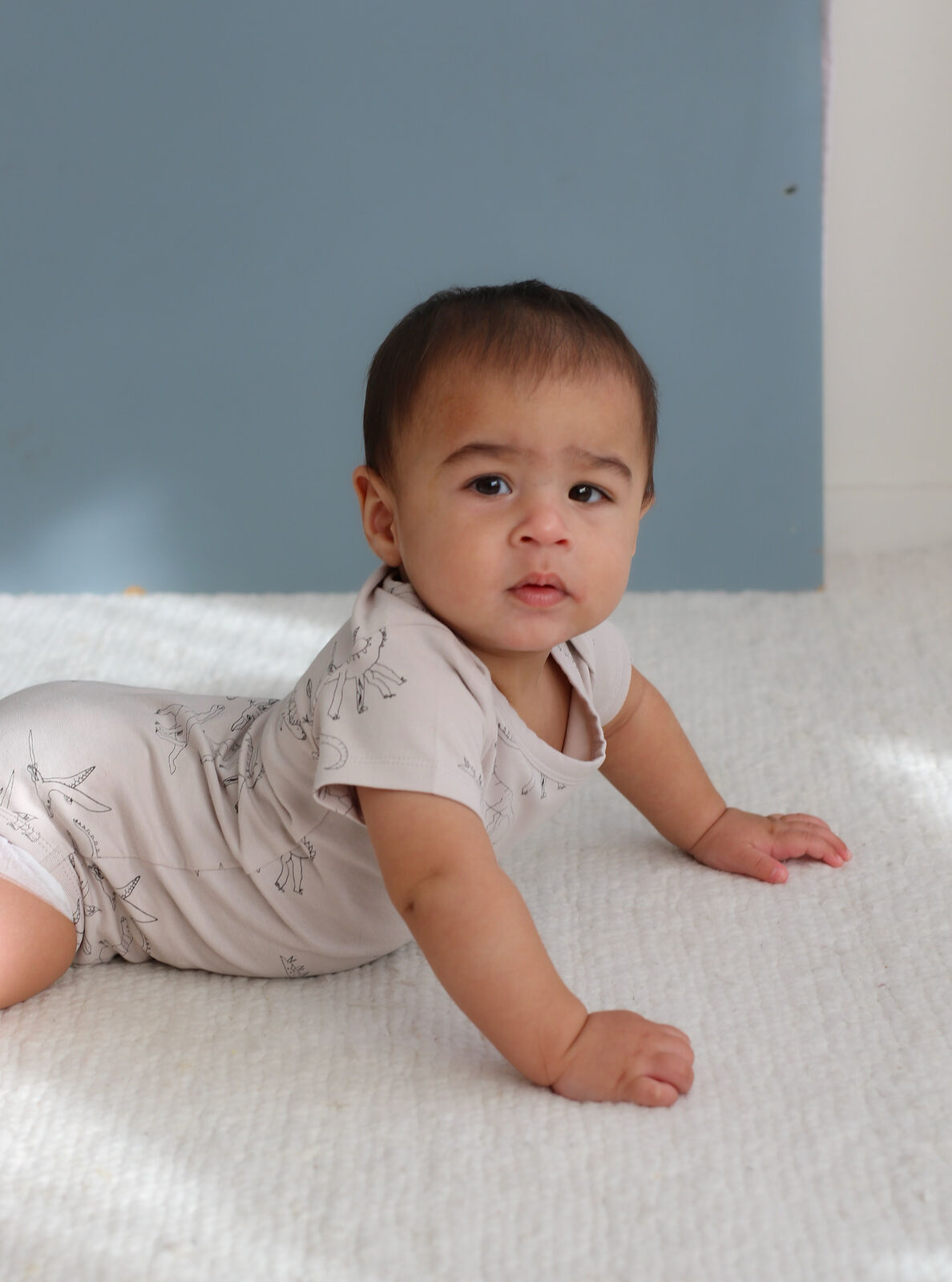Baby crawling on a white surface with a blue wall in the background