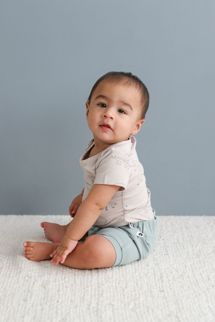 Baby sitting on a light gray surface with a plain background