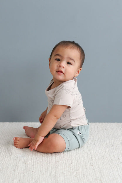 Baby sitting on a light gray surface with a plain background
