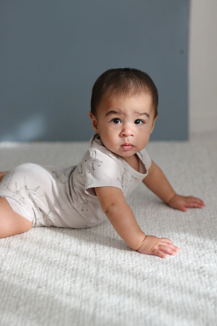 Baby crawling on a textured surface with a neutral background