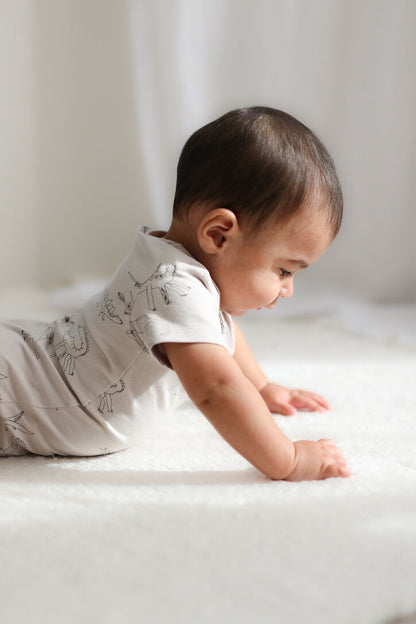 Baby in a white outfit crawling on a light-colored surface