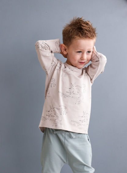 Child wearing a light-colored shirt with ruffled sleeves against a gray background