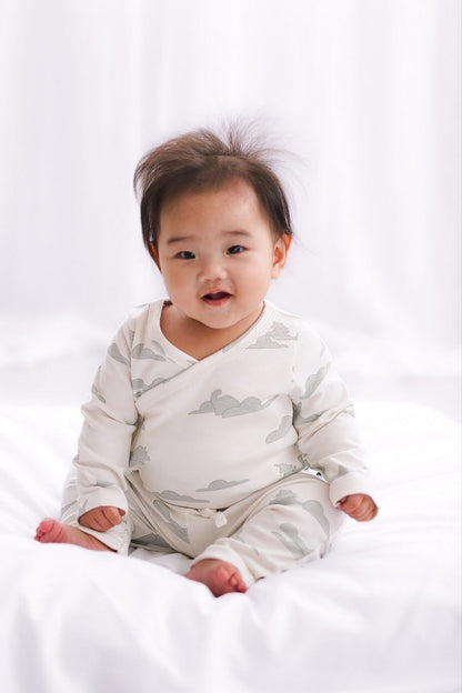 Baby wearing a white wrap with cloud pattern on a white background