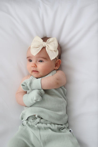 Baby in a light green outfit with a large bow on a white background