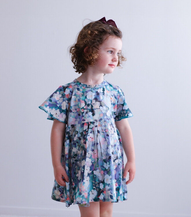 Young girl wearing a floral dress against a plain background