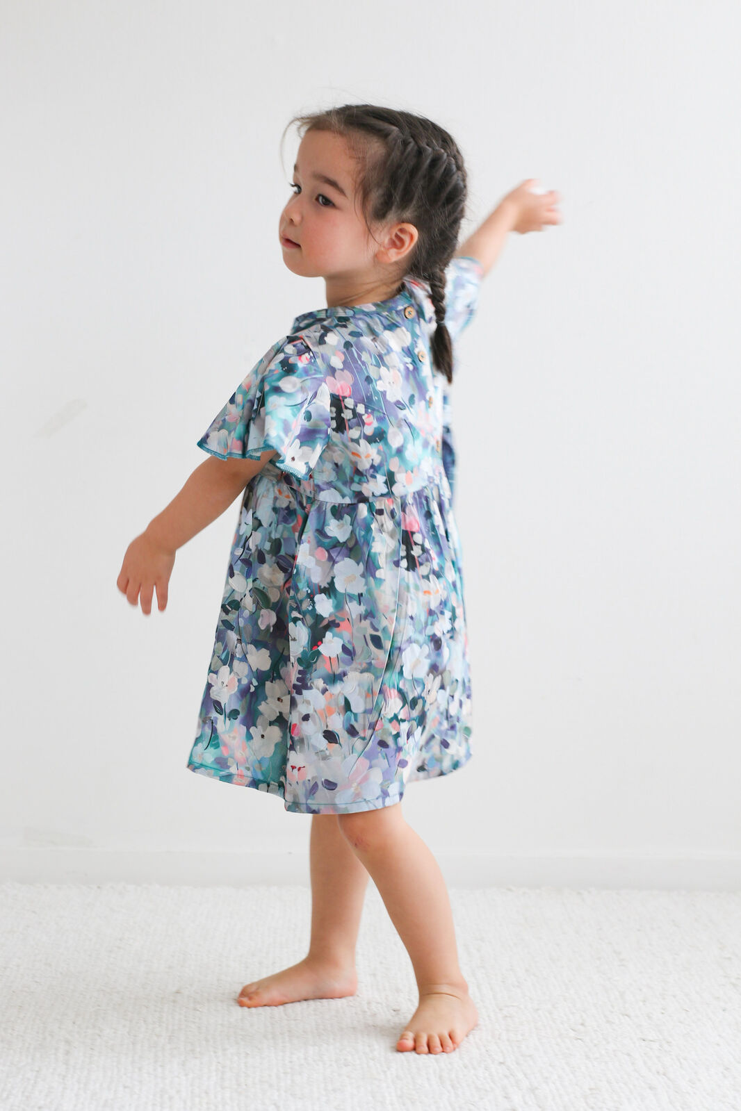 Child wearing a floral dress on a white background