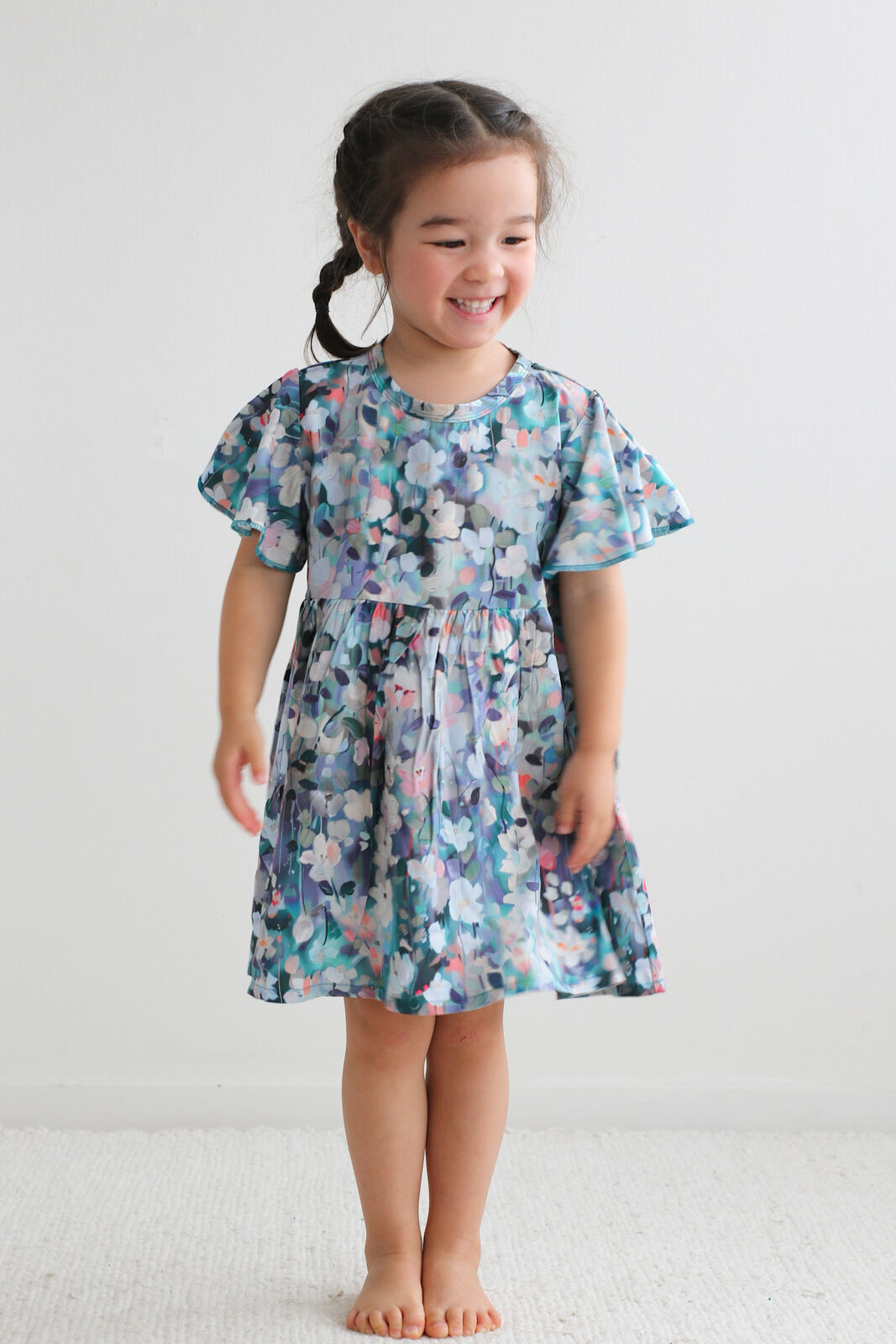 Young girl wearing a floral dress against a plain background