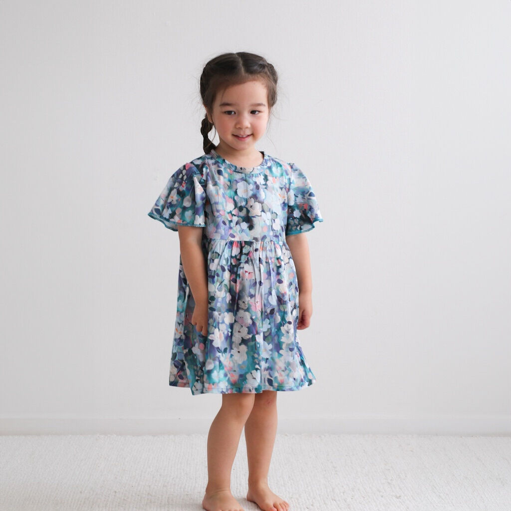 Young girl wearing a floral dress against a plain background